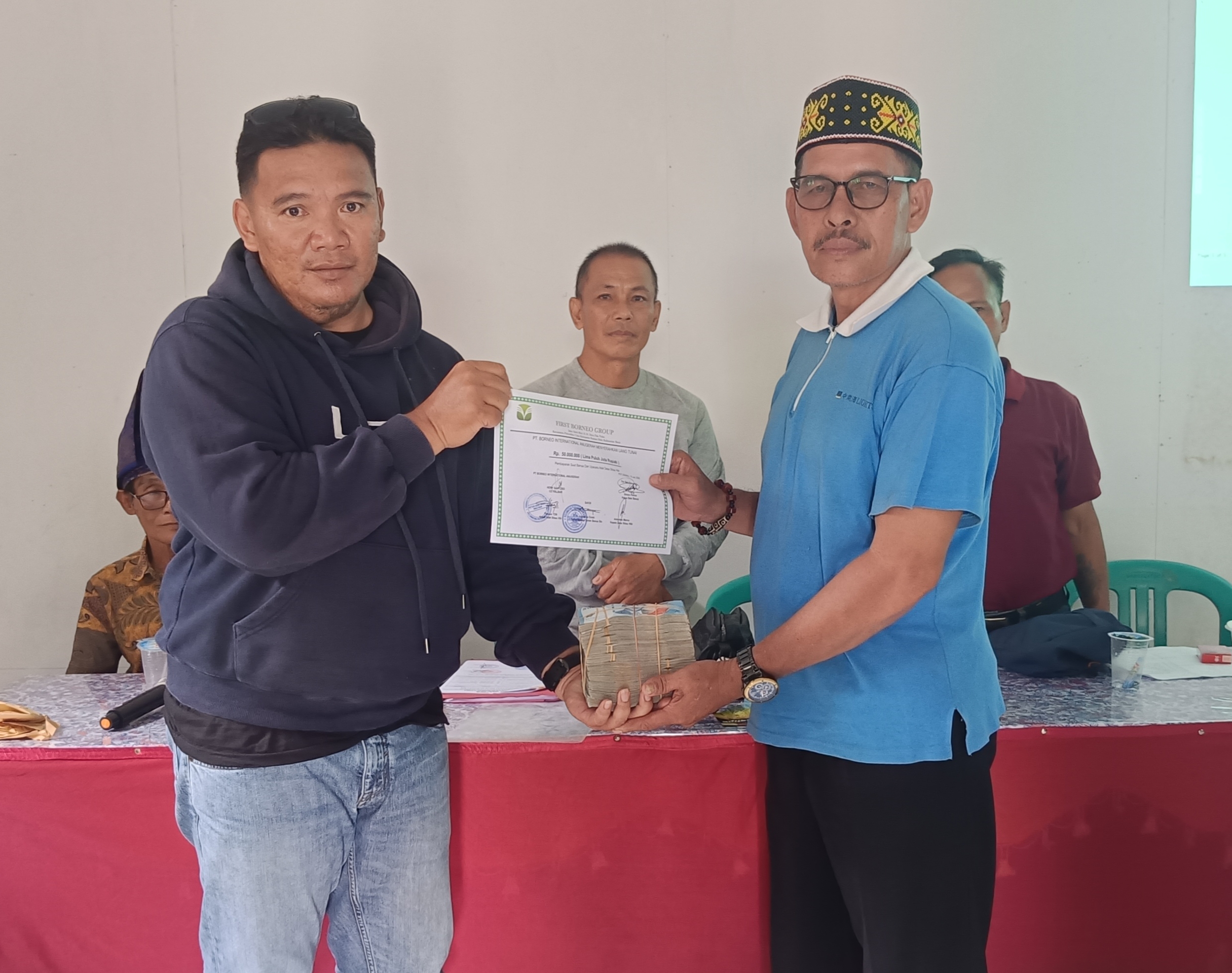 Perwakilan dari PT BIA saat menyerahkan uang sanksi adat untuk ritual adat kepada Ketua Tim Bela Banua Desa Sibau Hilir.